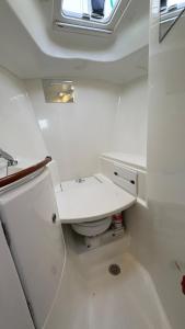 Un baño blanco con inodoro y ventana. en Voilier à quai, en Gruissan