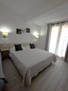 a white bedroom with a large bed and two windows at Bentus B&B in Villasimius