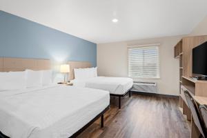 a hotel room with two beds and a flat screen tv at WoodSpring Suites Richmond Airport in Henrico +18 photos