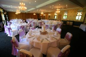 un salón de banquetes con mesas y sillas blancas y lámparas de araña en Cricklade House Hotel, Sure Hotel Collection by Best Western, en Cricklade