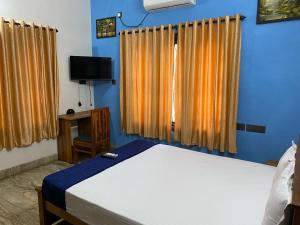 una camera con letto, TV e tende di Hotel O Varavoor Resort a Trichūr