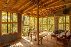 a screened in porch with a table and chairs at KIZUKI 子供の記憶にいつまでも思い出が残る場所 虫も天気も気にせず屋内bbq 遊具 大浴場 in Nasu