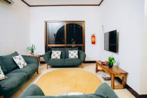 a living room with green couches and a table at Owens house in Dar es Salaam