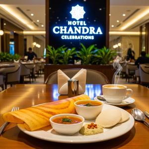 a table with a plate of food and two cups of coffee at Hotel Chandraa Celebration ISBT Dehradun in Dehradun