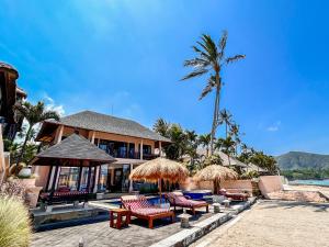 a resort with chairs and umbrellas on the beach at Villa Talia Vashti - Oceanfront villa with Private Sea Access, Pool & Cook in Candidasa