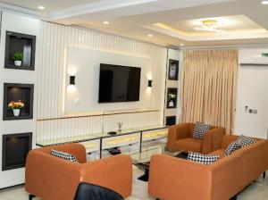 a living room with two chairs and a flat screen tv at MetroNest Apartments in Lekki
