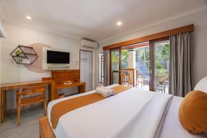 a bedroom with a bed and a desk and a television at Cove Belle Asana in Canggu