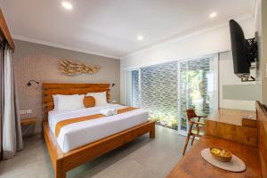 a bedroom with a bed and a television and a table at Cove Belle Asana in Canggu