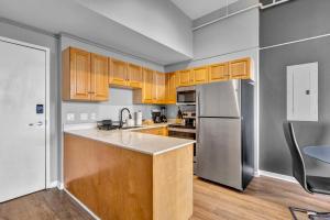 a kitchen with wooden cabinets and a stainless steel refrigerator at 1BR Loft Sauna & Walk to Theater & Campus in Cleveland +13 photos