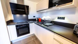 eine Küche mit weißen Schränken und schwarzen Arbeitsplatten in der Unterkunft Résidence L'ecrin - ECRIN A22 MAE-0131 in Arc 1800