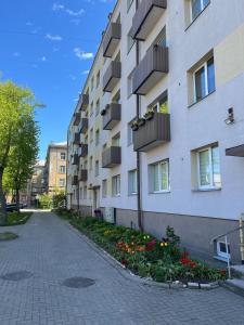 a building with balconies and flowers next to a street at Barinu Street Apartment in Liepāja
