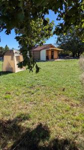 a house in a field with a tent in front at Le chalet du bien-être in Vailhourles