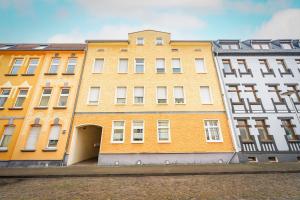 a large yellow building with an alley in front of two other buildings at Gemütliche Fachwerkwohnung mit Hängematte, Elbnah 300m in Magdeburg