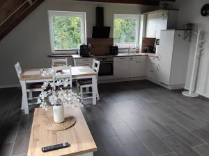 a kitchen with white cabinets and a table with flowers on it at Neue Welt Ferienwohnung 1 in Osteel +13 photos