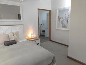 a bedroom with a white bed and a mirror at Bunya 4 Bedroom at On Burgum Pond Cottages in Maleny