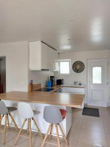una cucina con mobili bianchi e un piano di lavoro in legno di Jolie maison proche commodités, idéal vacances ou professionnels a Pleyben