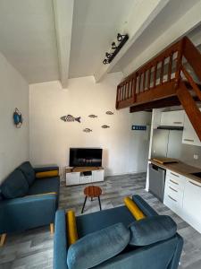 a living room with blue couches and a kitchen at Appartement avec loggia et mezzanine, bord de mer, 4 personnes in Argelès-sur-Mer