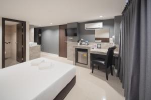 a hotel room with a bed and a desk at Grand Alpine Hotel in Bangkok