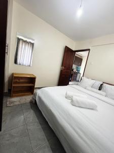 ein Schlafzimmer mit zwei Betten mit weißen Laken und einem Fenster in der Unterkunft Ikulu in Kisumu