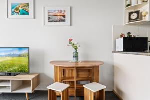 a living room with a tv and a table and stools at Apartment with Pool Access a minute to the Beach in Sydney +9 photos