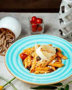 ein blauer Teller Pasta mit Käse auf einem Tisch in der Unterkunft BarnWay in Bischkek + 11 Fotos