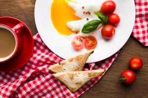 ein Teller mit Eiern und Tomaten und eine Tasse Kaffee in der Unterkunft BarnWay in Bischkek