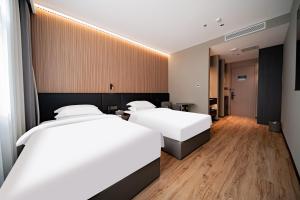 two beds in a hotel room with wooden floors at Xihe Langyue Hotel Beijing Changying Tianjie Branch in Beijing