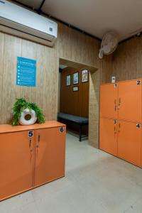 a locker room with orange lockers and a bench at Ghumakkads Hostel Near IGI Airport & Aerocity in New Delhi +5 photos