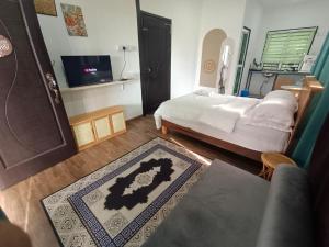 a bedroom with a bed and a tv and a rug at Rods Homestay - Kg Agong Penaga in Kepala Batas