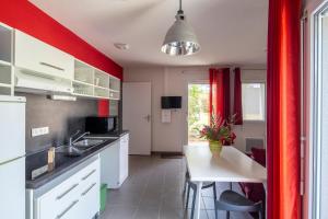 a kitchen with red walls and a small kitchen with a table at Village Vacances passion La Buissière in Labeaume