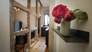 托尔高Altstadt Apartment in Torgau mit Balkon und Kunstgarten的房间柜台上放着一个插着红花的花瓶