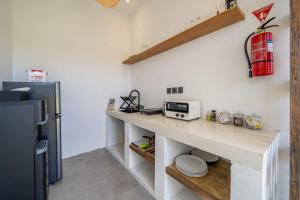 eine Küche mit einer Theke, einer Mikrowelle und einem Kühlschrank in der Unterkunft Peaceful 1BR Villa near Savaya & Uluwatu - V1 in Uluwatu + 17 Fotos