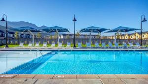 a large swimming pool with chairs and umbrellas at Family-Friendly 3-Story Home Sleeps 8 in American Fork