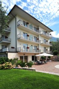 a large apartment building with tables and umbrellas at Hotel Garnì Orchidea in Malcesine