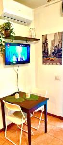 a table with chairs and a tv on a wall at TT House Rho Fiera Milano Station in Rho