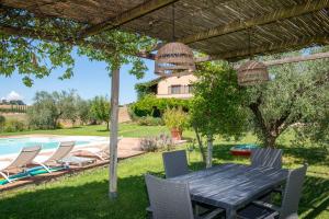 a table and chairs under a pergola next to a pool at Casale Farnia in Montecastrilli