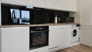 a kitchen with white cabinets and a washer and dryer at VacationClub - Siedem Wysp Apartament 31 in Sianozety
