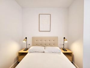 a bedroom with a bed with two lamps on two tables at Apartamentos Zaragoza Reconquista 3000 in Zaragoza