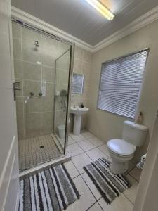 Un baño con ducha, inodoro y lavabo. en La'Ruach Guesthouse, en Rustenburg