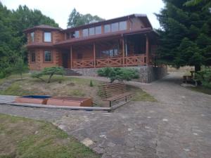 a large wooden house with a bench in front of it at Готель садиба ЗАТИШОК in Strilʼbichi