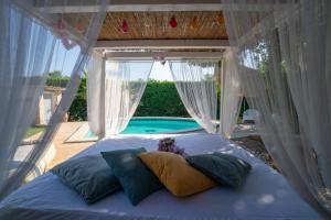 a bed with pillows in a room with a pool at Villa Letto D'Alloro - Royal Dream in Conversano