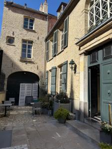 a brick building with doors and a courtyard with tables at Le Palais de la Cathédrale in Saint-Omer