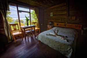 a bedroom with a bed and a table and a window at Paraíso Quetzal Lodge in Tres de Junio
