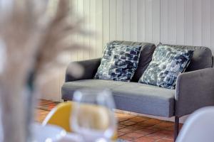 - un canapé avec deux oreillers et un verre de vin dans l'établissement Agapanthes jolie maison de ville à Rouen avec extérieur terrasse, à Rouen
