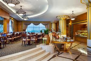 um restaurante com mesas e cadeiras num quarto em Corniche Hotel Abu Dhabi em Abu Dhabi