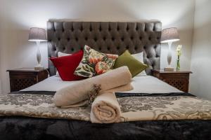 Una cama con muchas almohadas y un cabecero y dos lámparas. en Natures Way Bushbuck Cottage, en The Crags