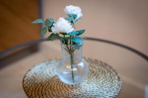 a glass vase with white flowers sitting on a table at Ceylan bel F2 à Rouen in Rouen +15 photos