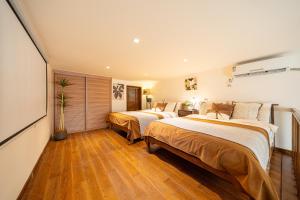 two beds in a room with wooden floors at Shanghai Hills & Well-time MCM Family B&B with Terrace Near Line2 Jing'an Temple in Shanghai