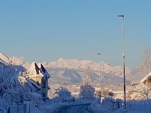 een gebouw bedekt met sneeuw met bergen op de achtergrond bij Mama's House in Cerklje na Gorenjskem