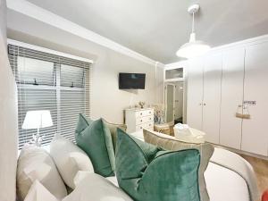een woonkamer met een witte bank en groene kussens bij Coastal Hospitality - Beach Club 205 in Mosselbaai